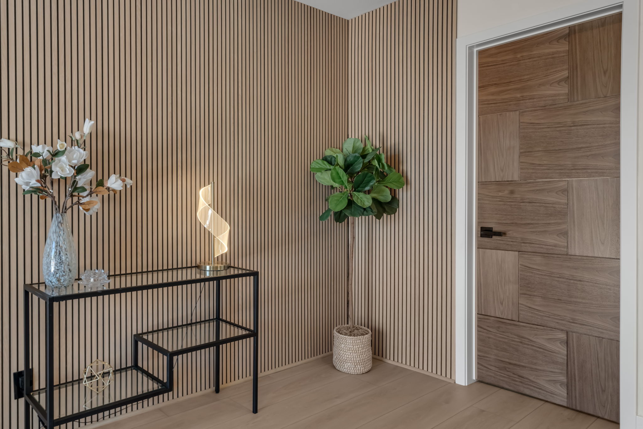 Foyer with slatted wood accent wall and geometric door